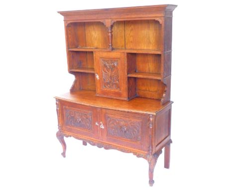 An early 20thC carved oak dresser, the raised plate rack with a central carved panel door, decorated with dragons, flanked by