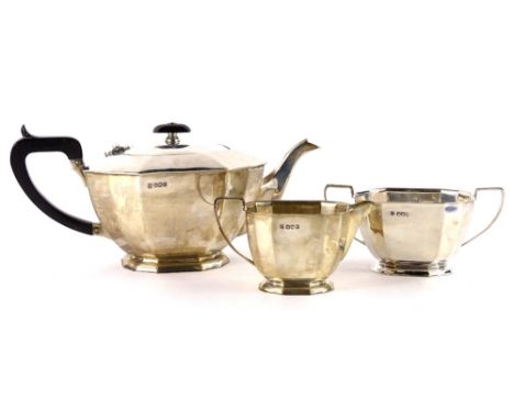 A George VI silver three piece tea set, of rectangular form with shaped corners, comprising teapot with ebonised composition 