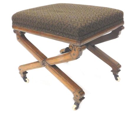 A Victorian walnut stool, with a padded seat and x shaped supports, on ceramic castors.