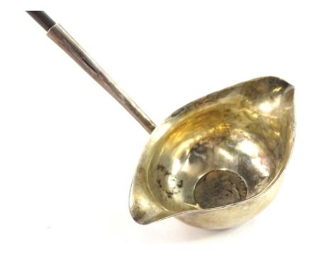 An early 19thC silver double lipped ladle, inset with a silver coin, date indistinct, and hallmark also indistinct, with twis