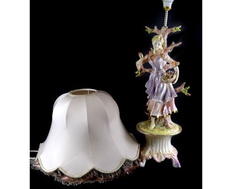 A Continental pottery table lamp, modelled in the form of a lady with basket of flowers etc., on a rococo scroll base, the sh