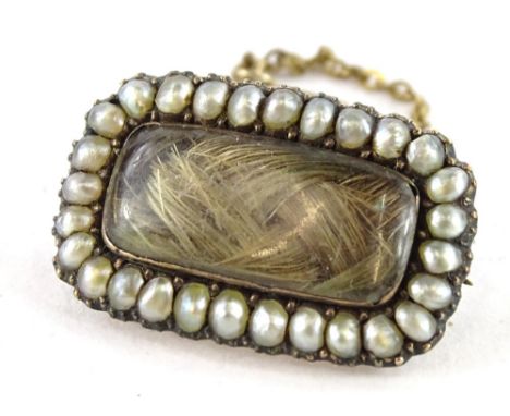 A Victorian memorial brooch, with rectangular window panel, with lockets of hair, with seed pearl surround, and safety chain,