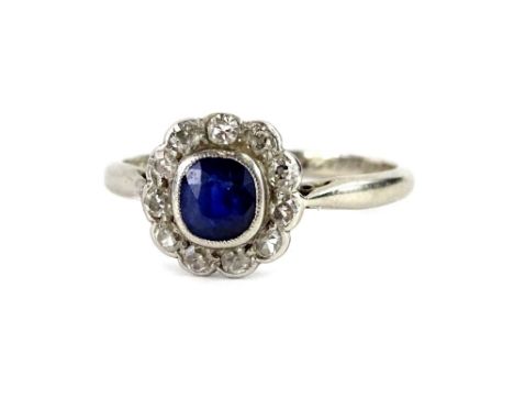 A sapphire and diamond floral cluster ring, with central small sapphire in rub over setting, surrounded by tiny diamonds, eac