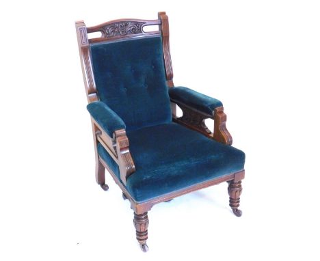 A late Victorian walnut armchair, with a button padded back, arm rests and seat, on shaped supports with part turned tapering