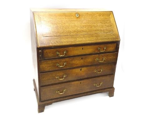 A George III oak bureau, the fall enclosing a fitted interior, above four graduated drawers with brass drop handles and brack