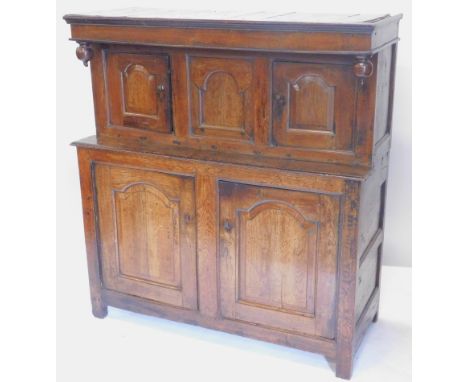 A 17thC oak duodarn, the raised back with three carved panel doors and drop finial's, the base with two panel doors on stiles