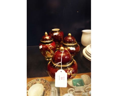 Three Carlton-ware Rouge Royale lidded urns and a vase with floral and peacock decoration 