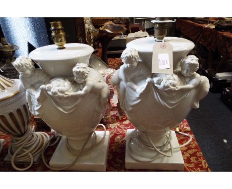 A pair of crackle glazed ceramic table lamps decorated with putti