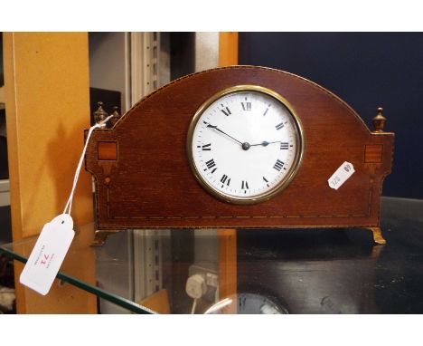 An Edwardian mahogany and satinwood inlaid mantel clock with enamelled dial having Roman numerals and brass finials and feet