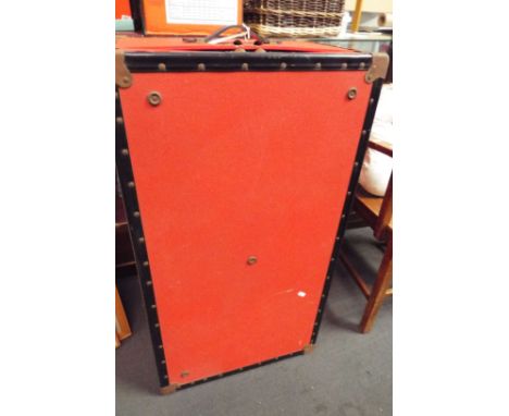 A red covered metal bound shipping trunk 