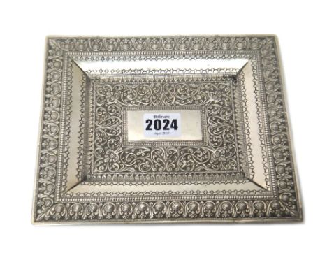 A Middle Eastern rectangular white metal dish, with a vacant central rectangular panel within a bold scrolling foliate border