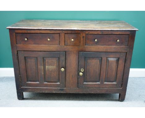 An early 18th century oak dresser base, with three drawers over a pair of double panel cupboards, 139cm wide x 92cm high. 
