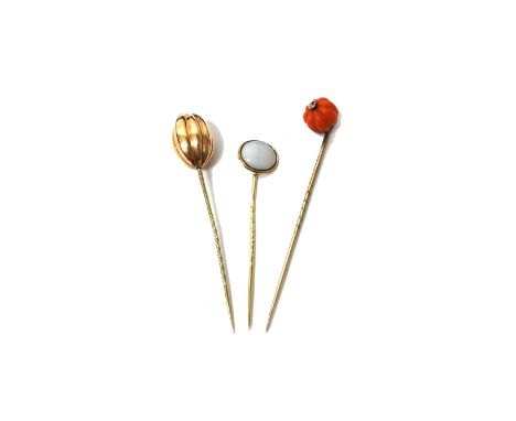 A gold stick pin, with a melon fluted coral bead terminal, a gold stick pin, with a fluted oval terminal and another stick pi