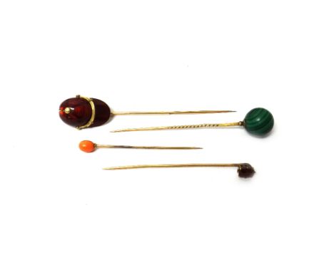 A gold and red enamelled stick pin, designed as a jockey's cap, a gold stick pin, with a malachite bead finial, a coral stick