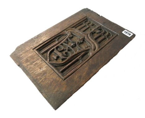 A 17th century oak blind tracery panel, relief carved with an armorial crest, 23.5cm wide x 34.5cm high.