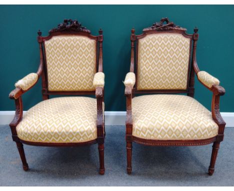 A pair of Louis XVI style carved walnut fauteuils, with arrow, quiver and torch crest rail, each 62cm wide x 100cm high (2). 