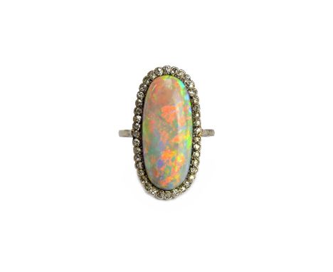 A white gold and platinum, opal and diamond ring, mounted with the oval opal to the centre, within a surround of cushion shap