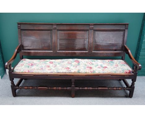 An early 18th century oak triple panel back open arm settle, on block and turned supports, 181cm wide x 101cm high.