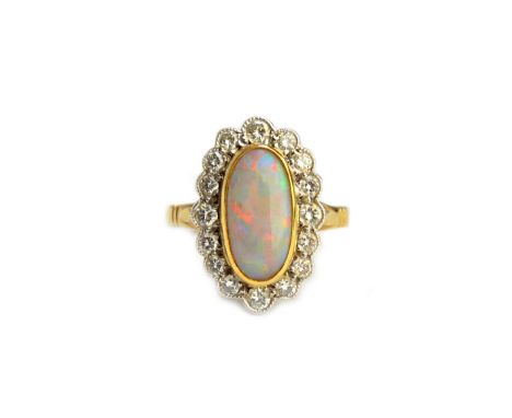 A gold, opal and diamond set oval cluster ring, collet set with the oval opal at the centre, in a surround of circular cut di