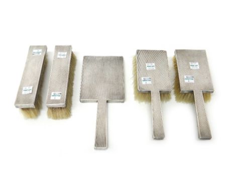 A lady's silver mounted five piece Art Deco dressing set, comprising; a hand mirror, a pair of clothes brushes and a pair of 