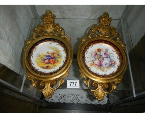 A pair of gilt framed ceramic wall plaques.