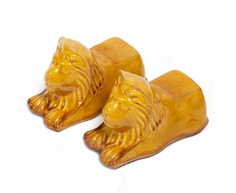 A PAIR OF LATE 19TH CENTURY POTTERY SASH WINDOW SUPPORTS  in the form of lions with a drip yellow glaze, 14.5cm (2)