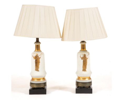 A PAIR OF WHITE GLASS TABLE LAMPS decorated with classical figures, each mounted on circular metal base and ebonised plinth, 