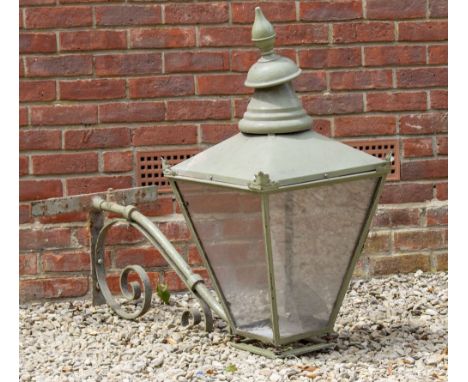 AN OLD GREEN PAINTED STREET LANTERN  with turned finial and square section tapering sides, complete with a scrolling wrought 