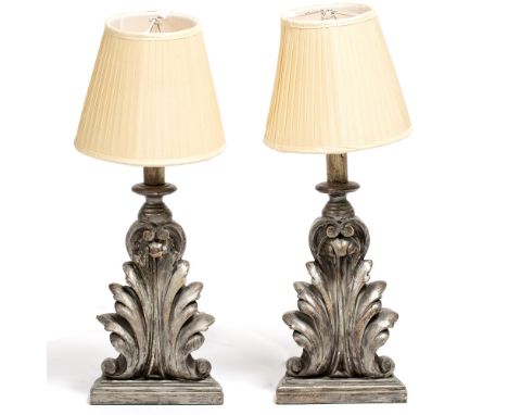 A PAIR OF SILVERED CARVED WOOD TABLE LAMPS in the form of acanthus leaf brackets, each lamp with a 'D' shaped base 18cm wide 