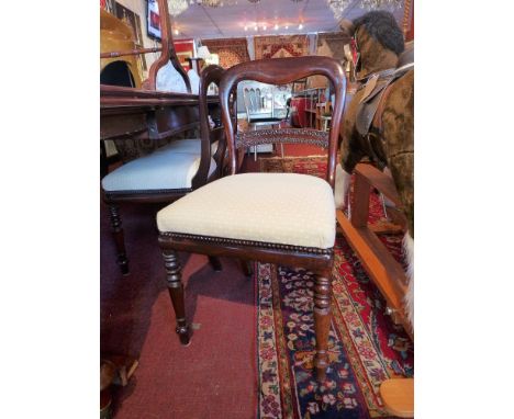 A set of six mahogany dining chairs having a carved bar to the back, upholstered in ivory fabric, raised on turned supports