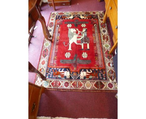 A South West Persian Qashqai rug 172cm x 122cm depicting peasopolice figural motifs on a terracotta field within stylised flo