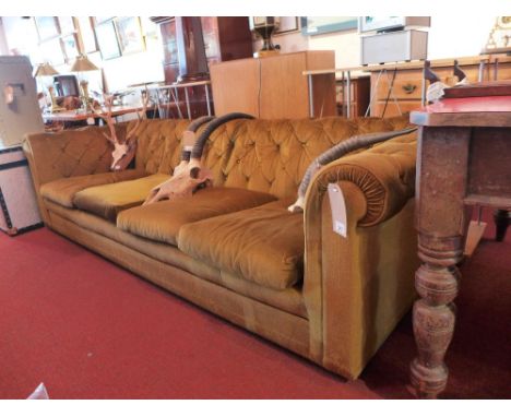 A 20th Century four seater sofa with green velour button back upholstery and raised on castors H:64cm W:240cm D:86cm