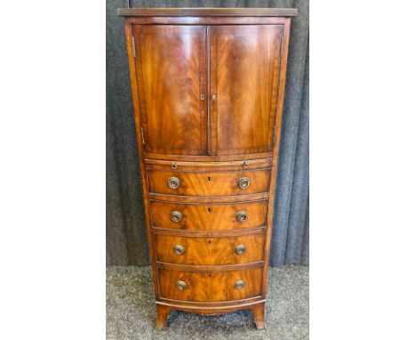 A 19th century flame mahogany chest, the bow front surface above two cupboard doors opening to shelved interior, the lower wi