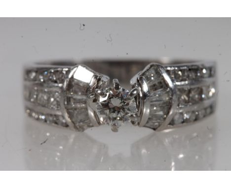 White metal diamond solitaire set ladies ring, the central single stone in claw setting flanked by baguette cut diamonds and 