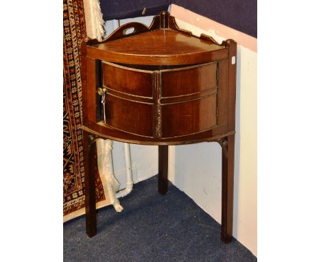 A George III mahogany bow front corner cupboard, with shaped gallery and panelled door, raised on square legs with pierced br