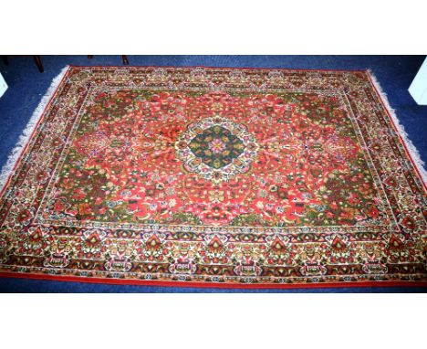 A Kashan style carpet, the central medallion over red ground, with allover floral decoration and green spandrels with elabora