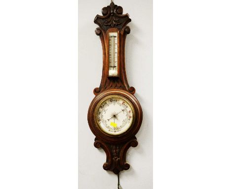 A Victorian oak cased aneroid barometer, with scroll cresting rail, above a thermometer and barometer dial, 62cms high. 