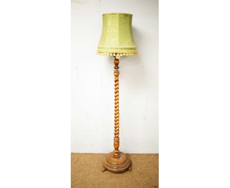 An early 20th Century oak standard lamp, the central barley twist column raised on a dished circular base with out-swept feet