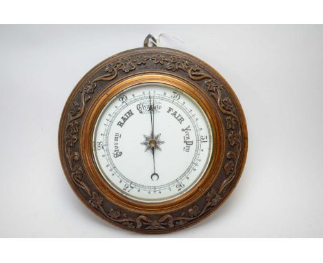 Early 20th century oak barometer, the 7.5 inch white enamel dial contained within a copper bezel enclosed by a carved border 
