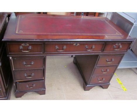 A reproduction mahogany pedestal desk, the rectangular top inset with a maroon leather panel above a central drawer and two b