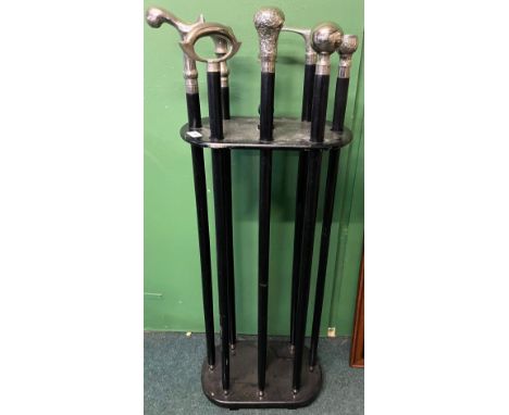Cane holder with eight white metal mounted black wooden canes of various designs to include five ball top canes, one with an 