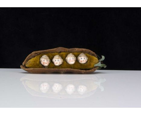 A late 19th century four bisque heads in a pea-pod pincushion,  the four bisque children heads with light brown painted and m