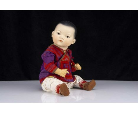A large Armand Marseille 353 Asian baby, with brown glass eyes, light brown complexion, closed mouth, black painted hair, ben