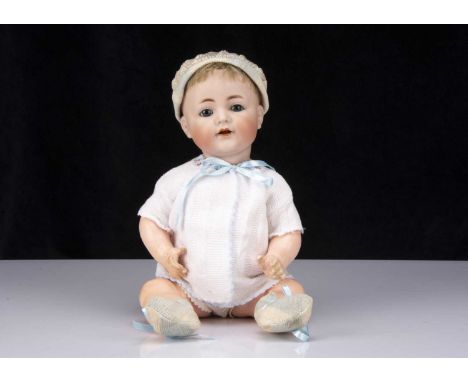 A Kammer & Reinhardt 128 character baby,  with blue sleeping eyes, blonde mohair wig, bent-limbed composition body, white cot