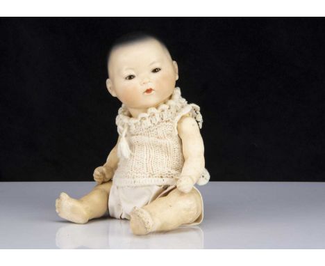 A small Armand Marseille 353 Asian baby, with brown glass eyes, light brown complexion, closed mouth, black painted hair, ben