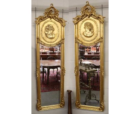 A Pair of Neo Rococo Style Gilt Framed Mirrors, with arched tops, decorated in relief with portrait medallions, 179cm by 53cm
