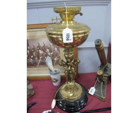 Brass Oil Lamp, the well supported by two cherubs, on black glaze stepped base.