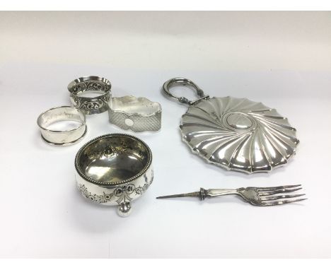 A small collection of silver items including a silver backed hand mirror, three napkin rings, table salt and a fork (missing 