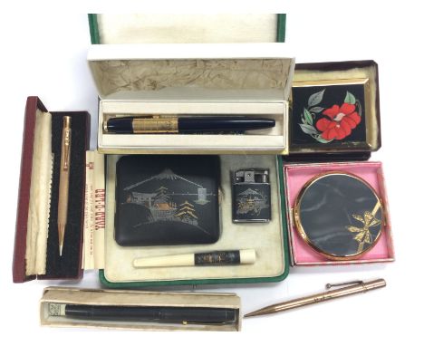 A cased Oriental cigarette case, holder and lighter set plu compacts and various pens.