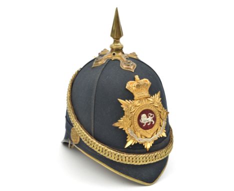 A Victorian officer’s blue cloth spiked helmet of The King’s Own (Royal Lancaster Regiment), brass peak binding, top mount an